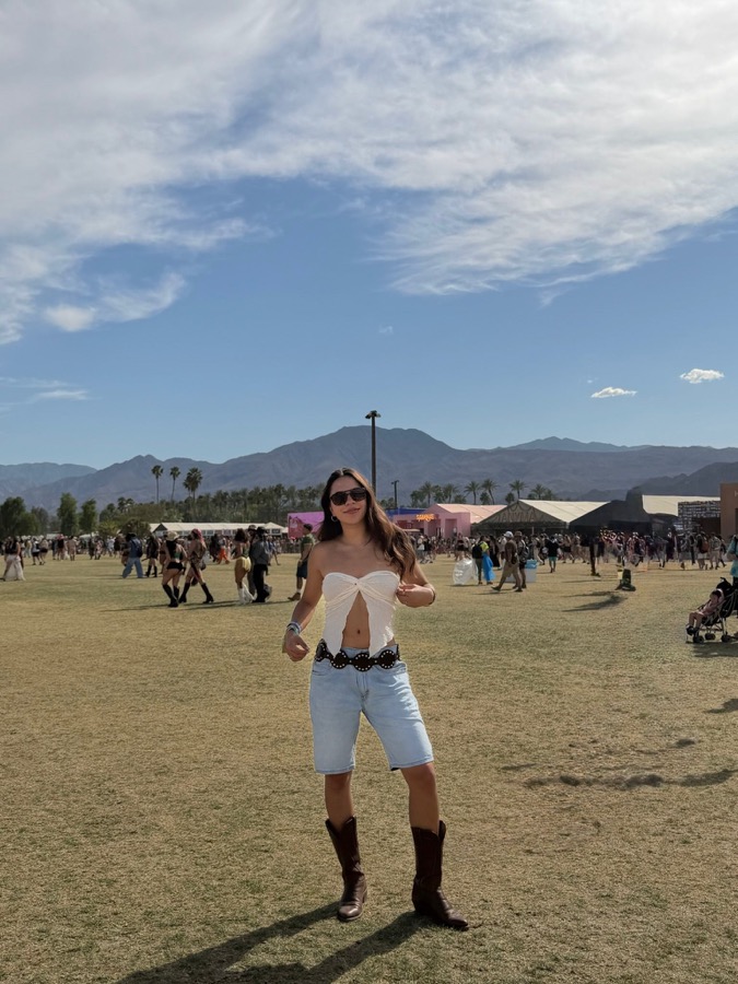 A festival-goer in a white tie-front top, denim shorts, and cowboy boots at Coachella